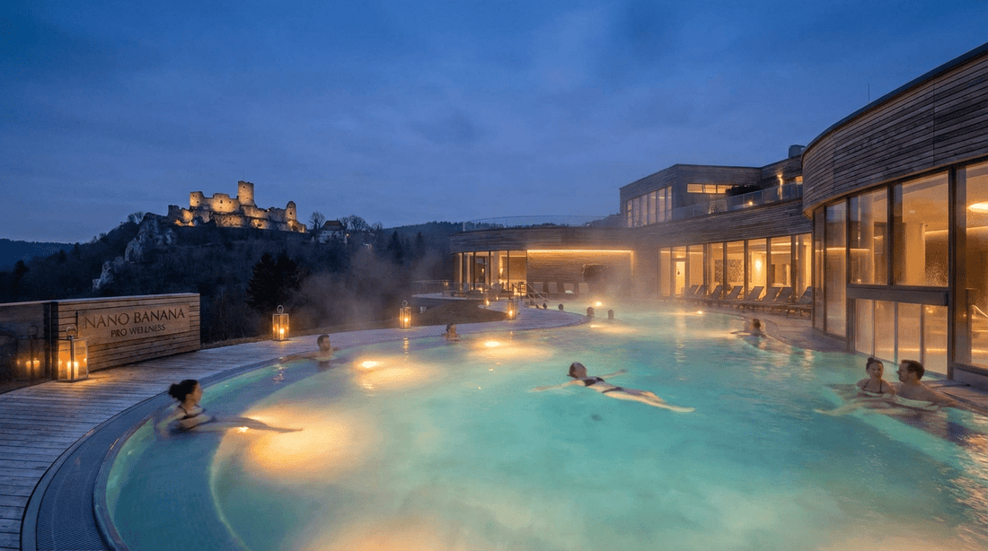 Panorama Therme Beuren Außenbecken bei Dämmerung mit Blick auf die Burgruine Hohenneuffen und dampfendem Thermalwasser