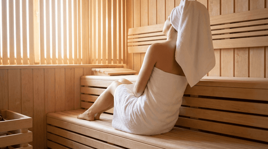 Person sitzt entspannt in finnischer Sauna mit geschlossenen Augen und ruhiger Atmung