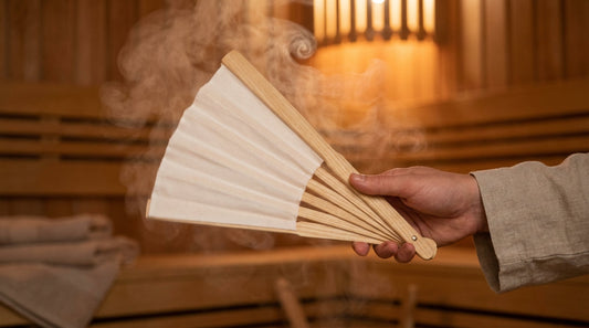 Professioneller Aufgussfächer aus hellem Eschenholz mit weißer Baumwollbespannung verteilt aromatischen Dampf in einer finnischen Sauna